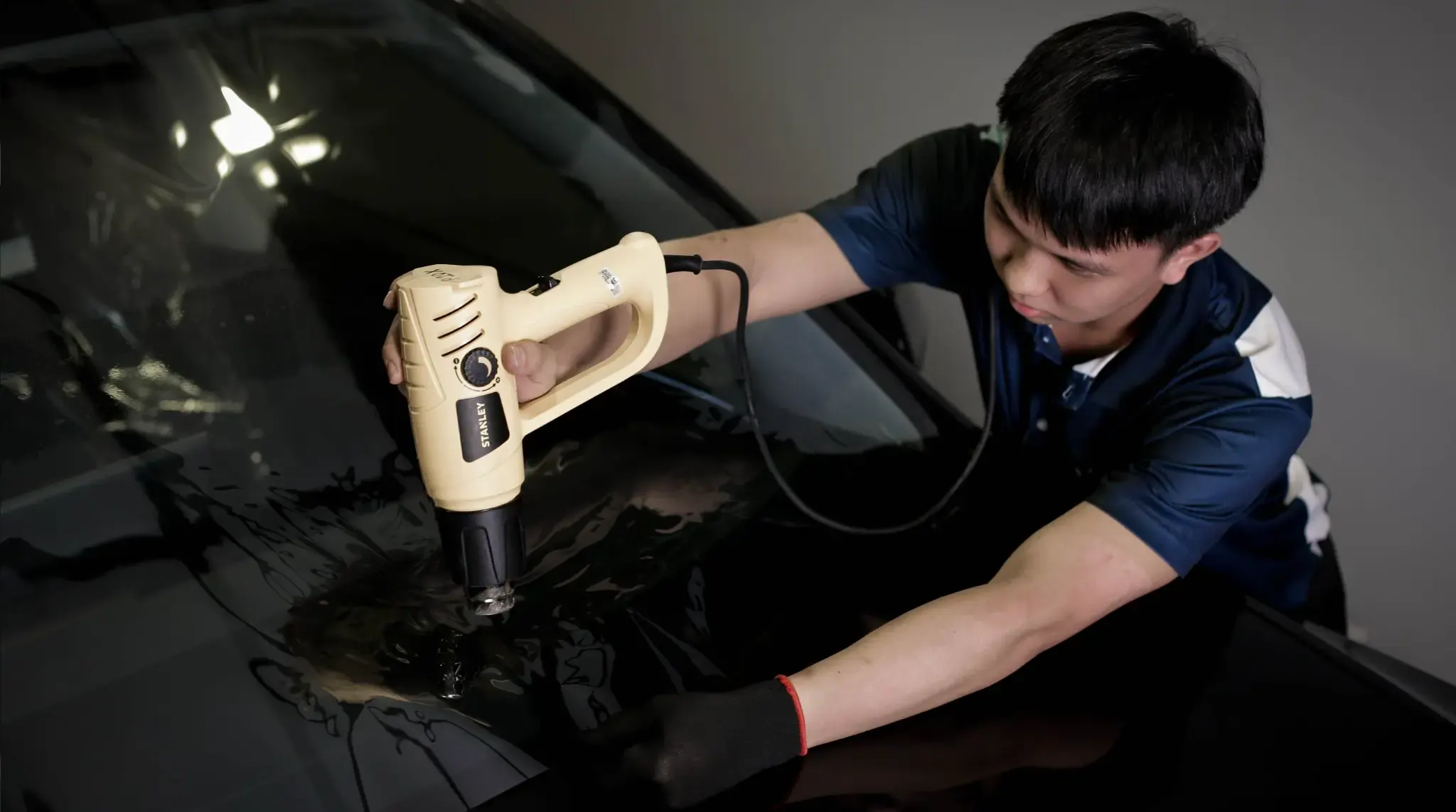 Juruteknik mengecutkan filem tinted pada cermin kereta