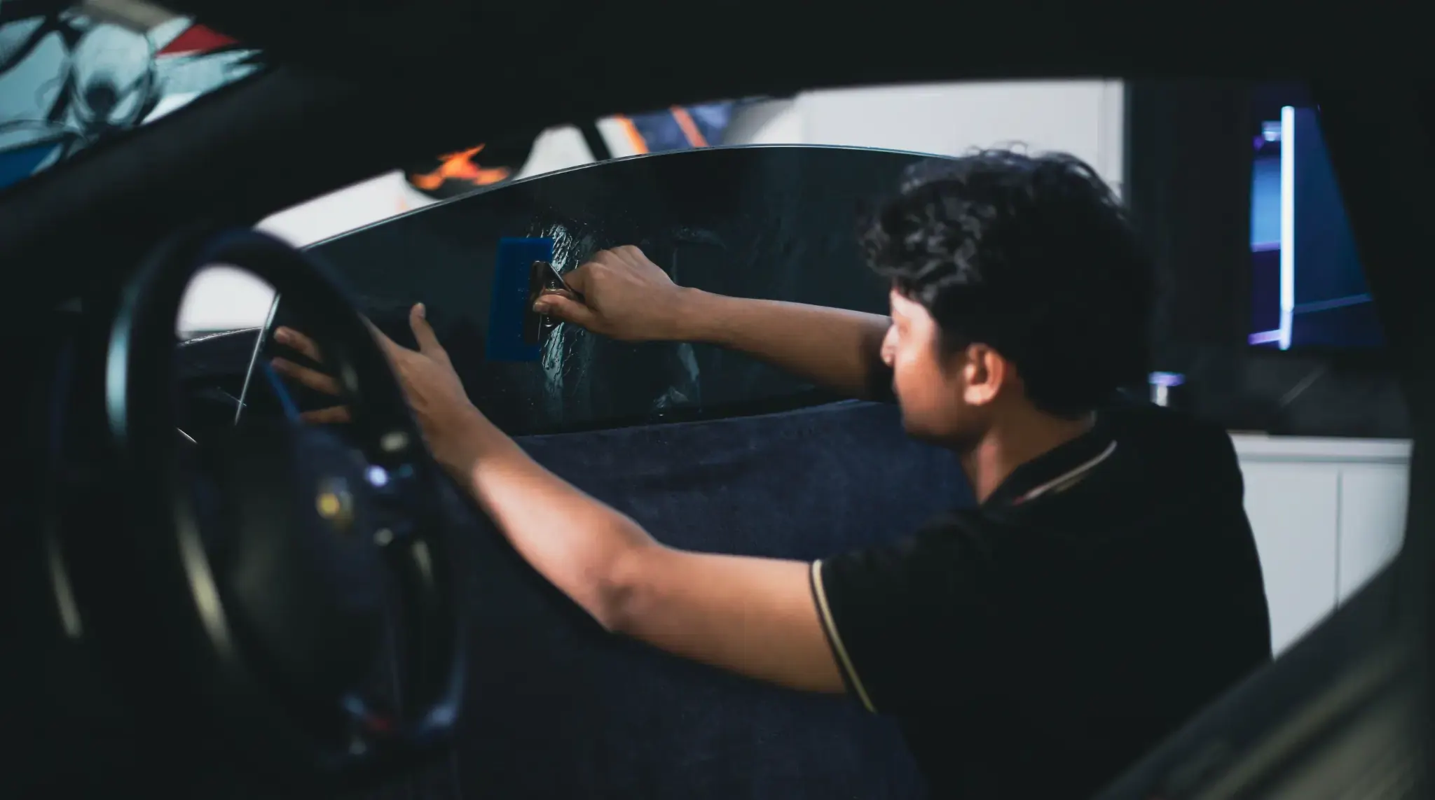 Juruteknik memasang filem tinted pada cermin kereta